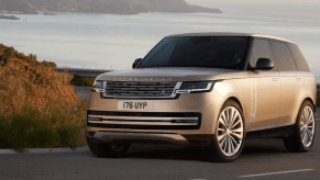 A 2024 Land Rover Range Rover 4x4 midsize luxury SUV model on a curving highway road overlooking the sea
