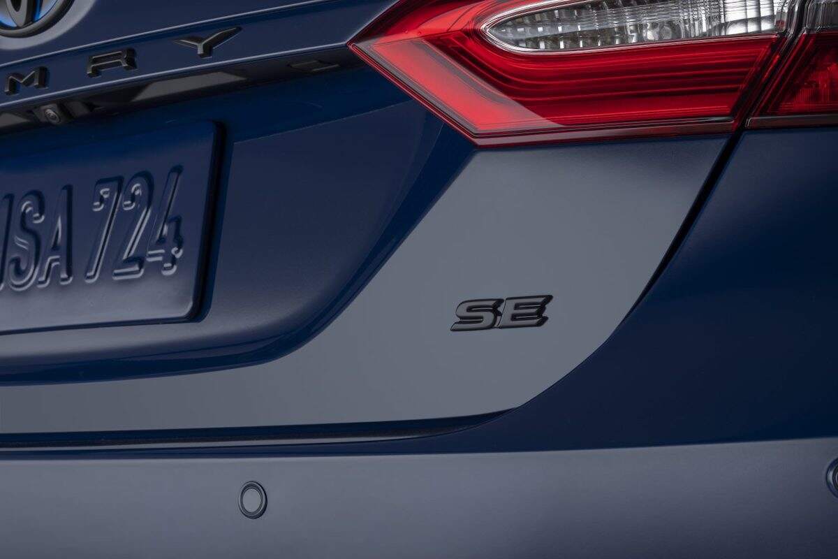 The 'SE' badge on the back of a blue 2024 Toyota Camry SE trim