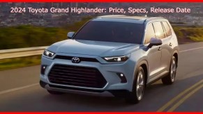 A white 2024 Toyota Grand Highlander midsize SUV is driving on the road.