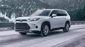 A white 2024 Toyota Grand Highlander is driving on the road.