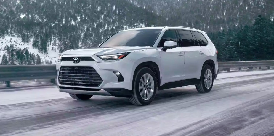 A white 2024 Toyota Grand Highlander is driving on the road. 