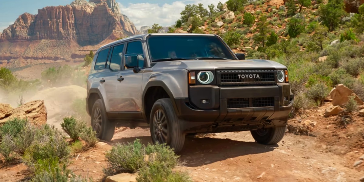A gray 2024 Toyota Land Cruiser midsize SUV is driving off-road.