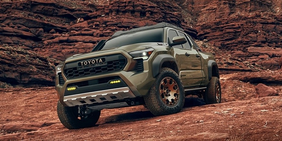 A green 2024 Toyota Tacoma midsize pickup truck is parked off-road. 