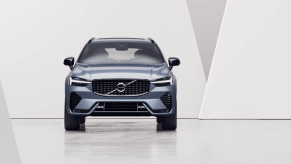 A promotional shot of a 2024 Volvo XC60 compact luxury SUV model as a woman stares at its profile
