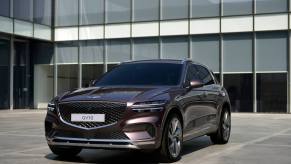 The Genesis GV70 parked in front of an office building. This is the most affordable Genesis SUV available.