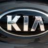 A silver Kia logo on the front of a car.