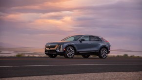 Driver side of the 2023 Cadillac LYRIQ in silver driving at dusk. The Lyriq is the premier Cadillac EV