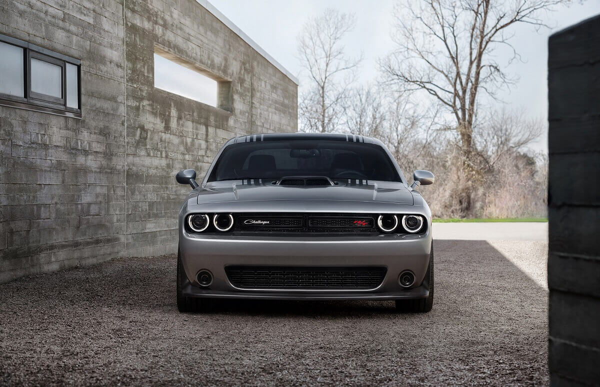 A silver and black Dodge Challenger R/T Scat Pack shows off its shaker hood by a modern home.