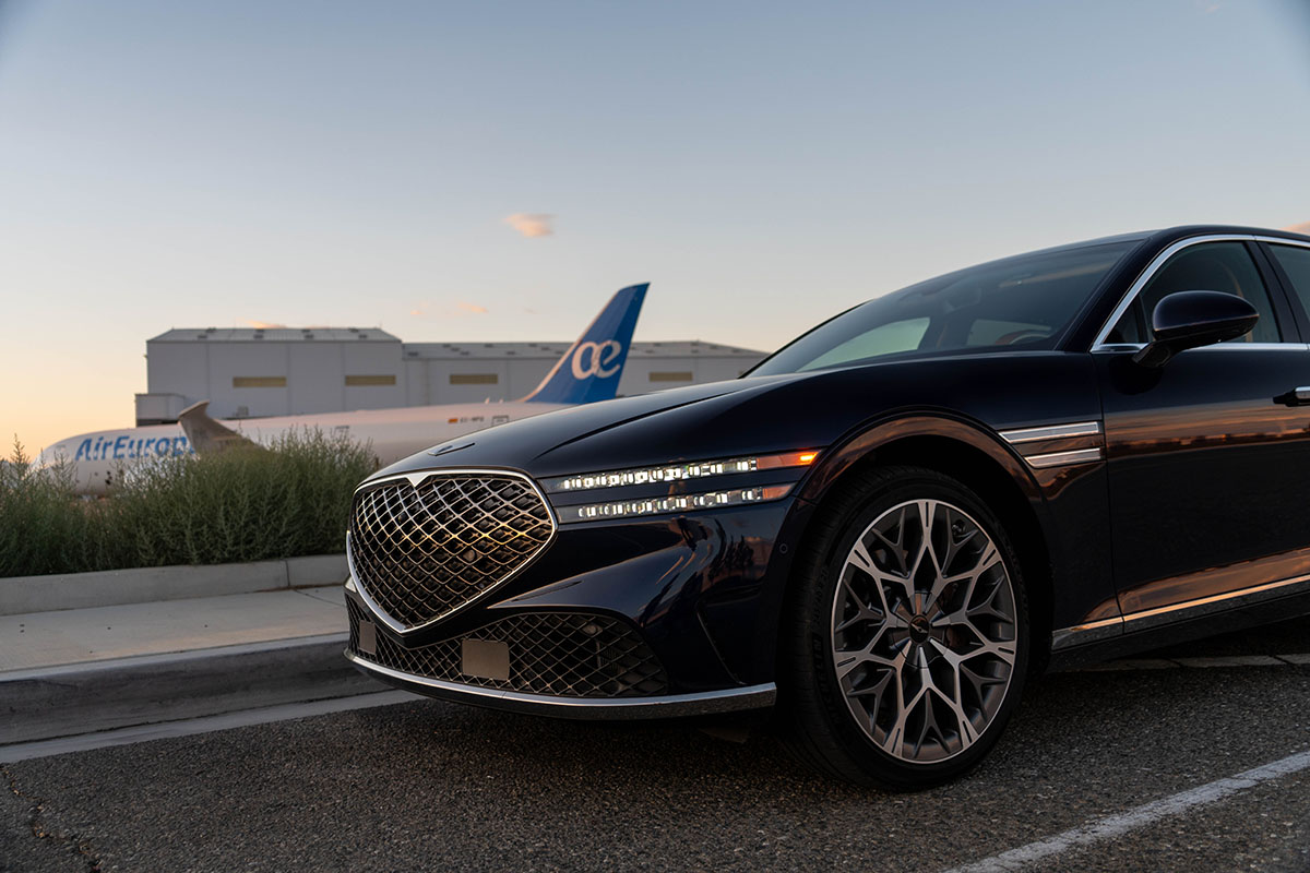 Genesis G90 front end with DRLs on parked in front of Boeing 787