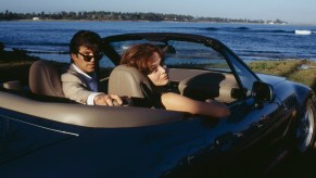 Pierce Brosnan and Izabella Scorupco pose with the movie car on set of a James Bond movie in a BMW Z3.