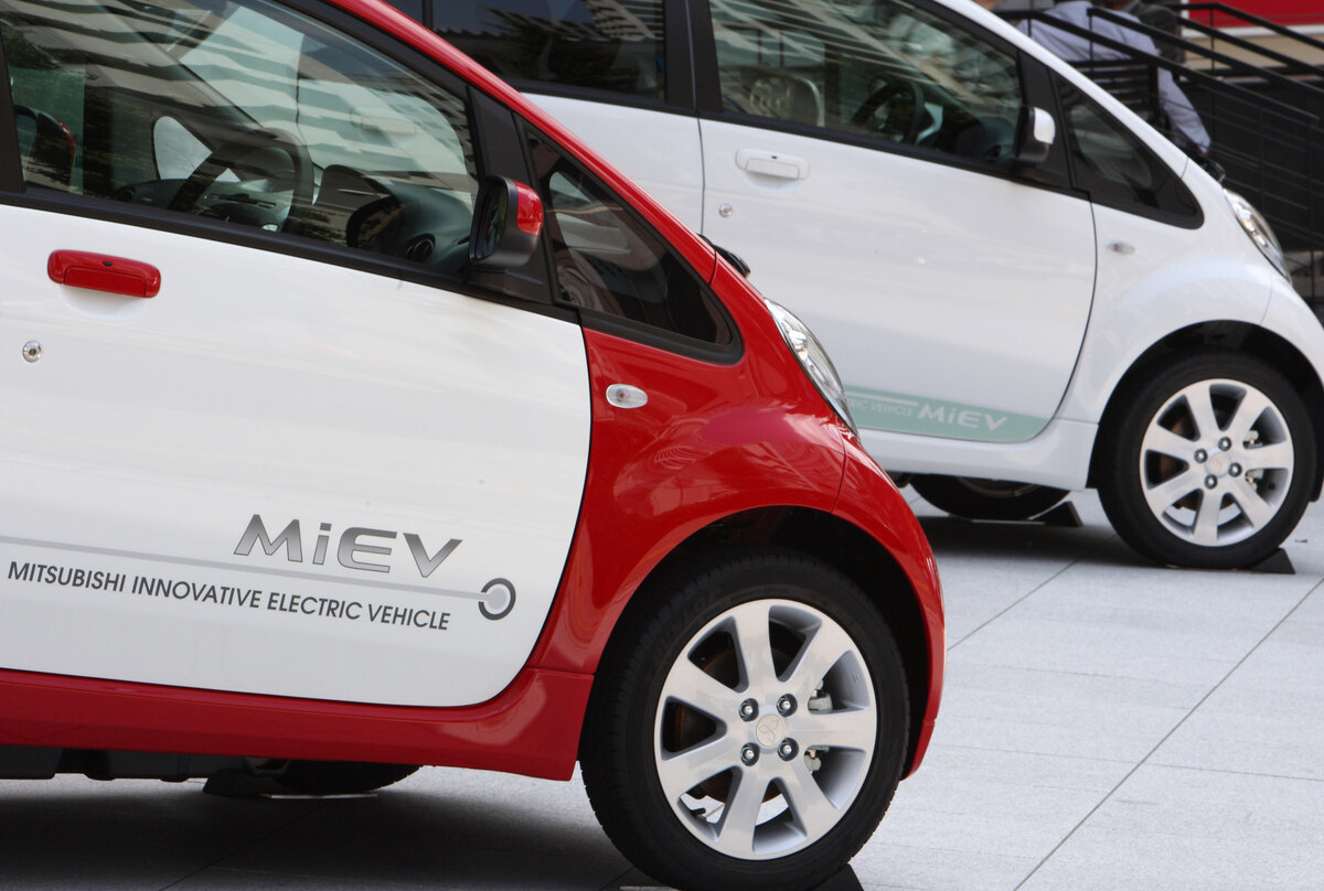 a white and red 2012 Mitsubishi i-MiEV EV in front of a white one