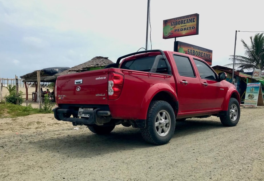 The rear end of a Wingle pickup truck by Chinese "Great Wall Motors" parked in front of a beach restaurant in Ecuador.