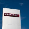 The Haval logo on a sign above a dealership, a blue sky in the background.