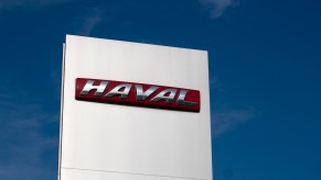 The Haval logo on a sign above a dealership, a blue sky in the background.