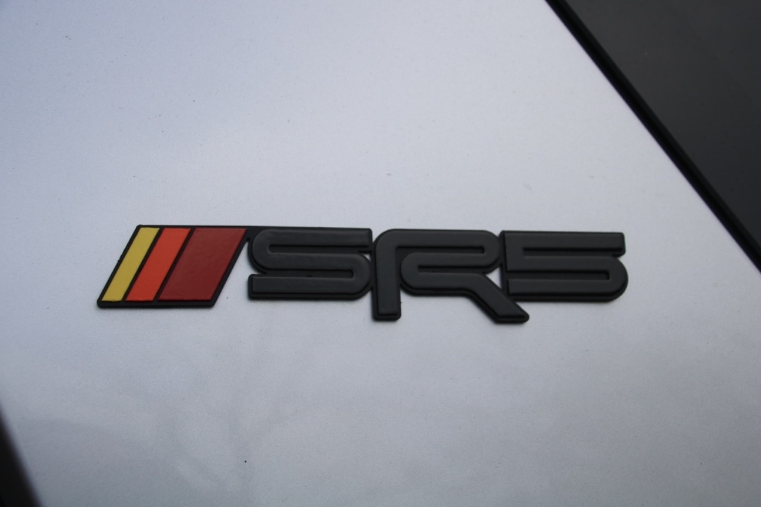 A 2023 Toyota Tacoma SR5 badge with tri-colored heritage racing stripes.