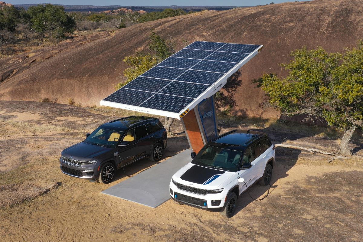 The Summit Reserve (L) and Trailhawk (R) of the 2024 Jeep Grand Cherokee 4xe plugged into a solar panel EV charger