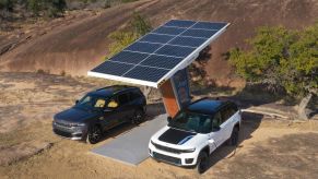The Summit Reserve (L) and Trailhawk (R) of the 2024 Jeep Grand Cherokee 4xe plugged into a solar panel EV charger