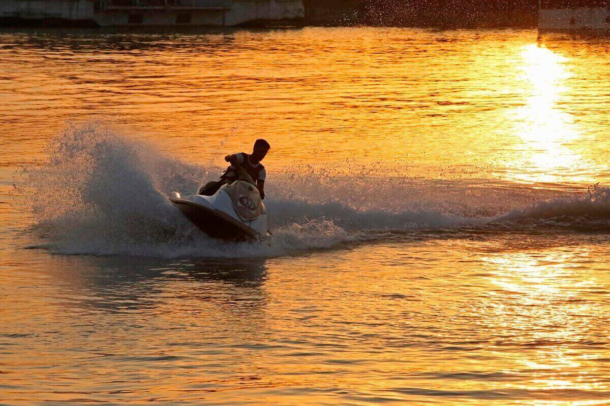 A jet ski shows how long it can make smiles last as it kicks up spray at sunset.