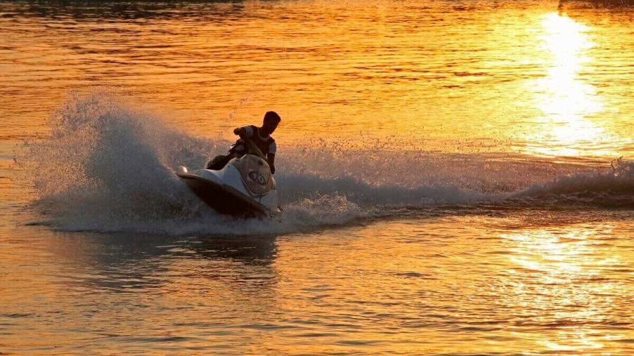 A jet ski shows how long it can make smiles last as it kicks up spray at sunset.