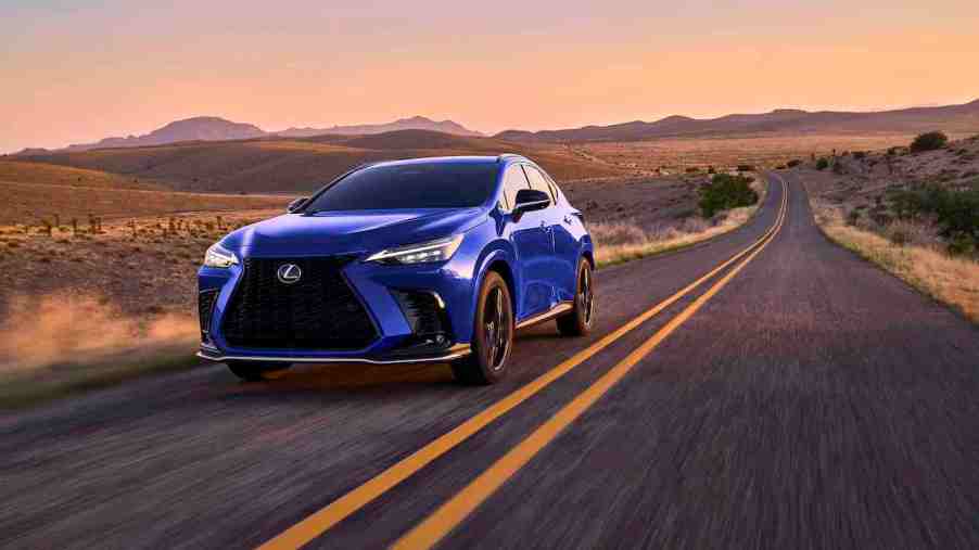 A blue 2024 Lexus NX 450h driving along a desert road at sunset. This is one of the Lexus Hybrid SUVs that falls short to the Porsche Cayenne.