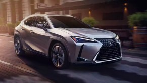 A gray 2023 Lexus UX luxury subcompact hybrid SUV is driving on the road.