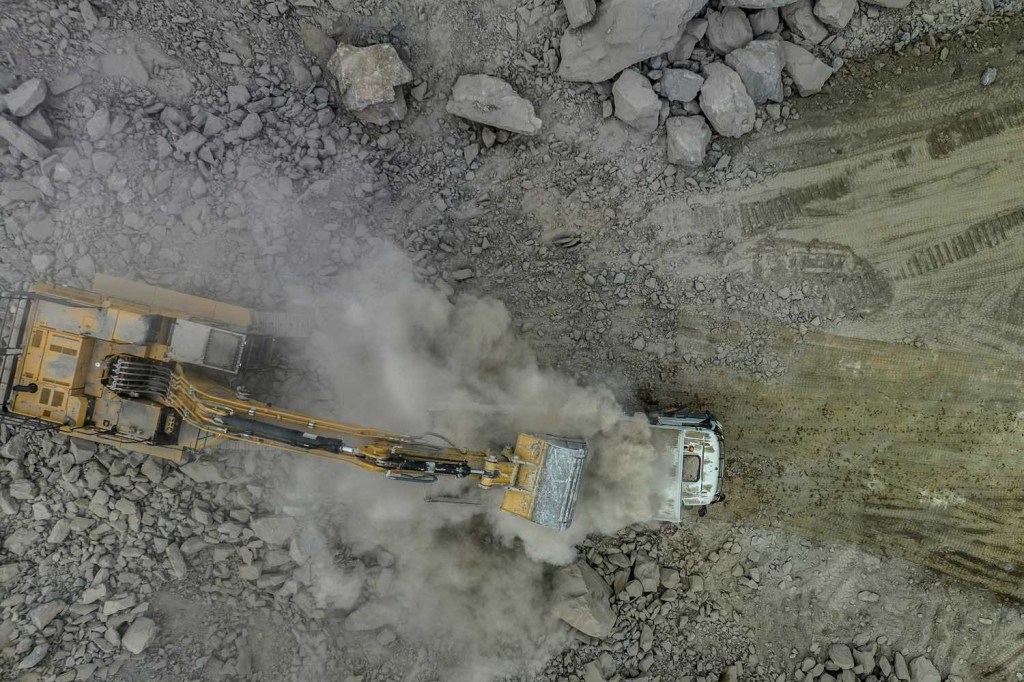Construction equipment moves rocks in a lithium mine to produce lithium-ion EV batteries in Brazil.