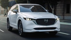 A white 2024 Mazda CX-5 small SUV is driving on the road.