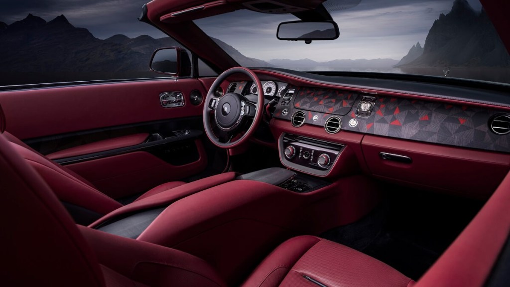 The open-air cabin of the Rolls-Royce La Rose Noire Droptail luxury car reveals a wristwatch and red interior.