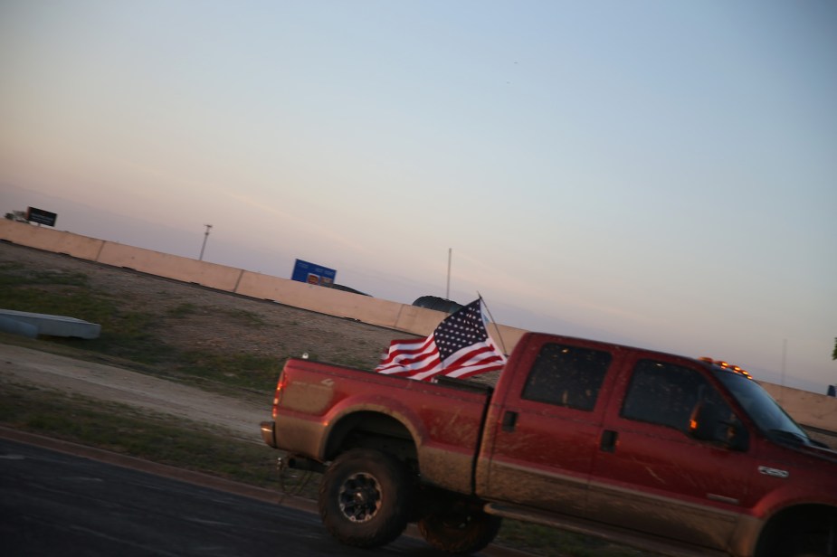Heavy-duty Ford pickup truck driving along the highway with a U.S.A. flag in its bed.