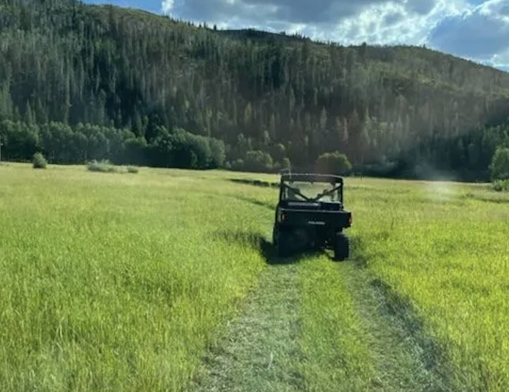 The 2024 Polaris Ranger XD driving in a field near the base of the mountains. 