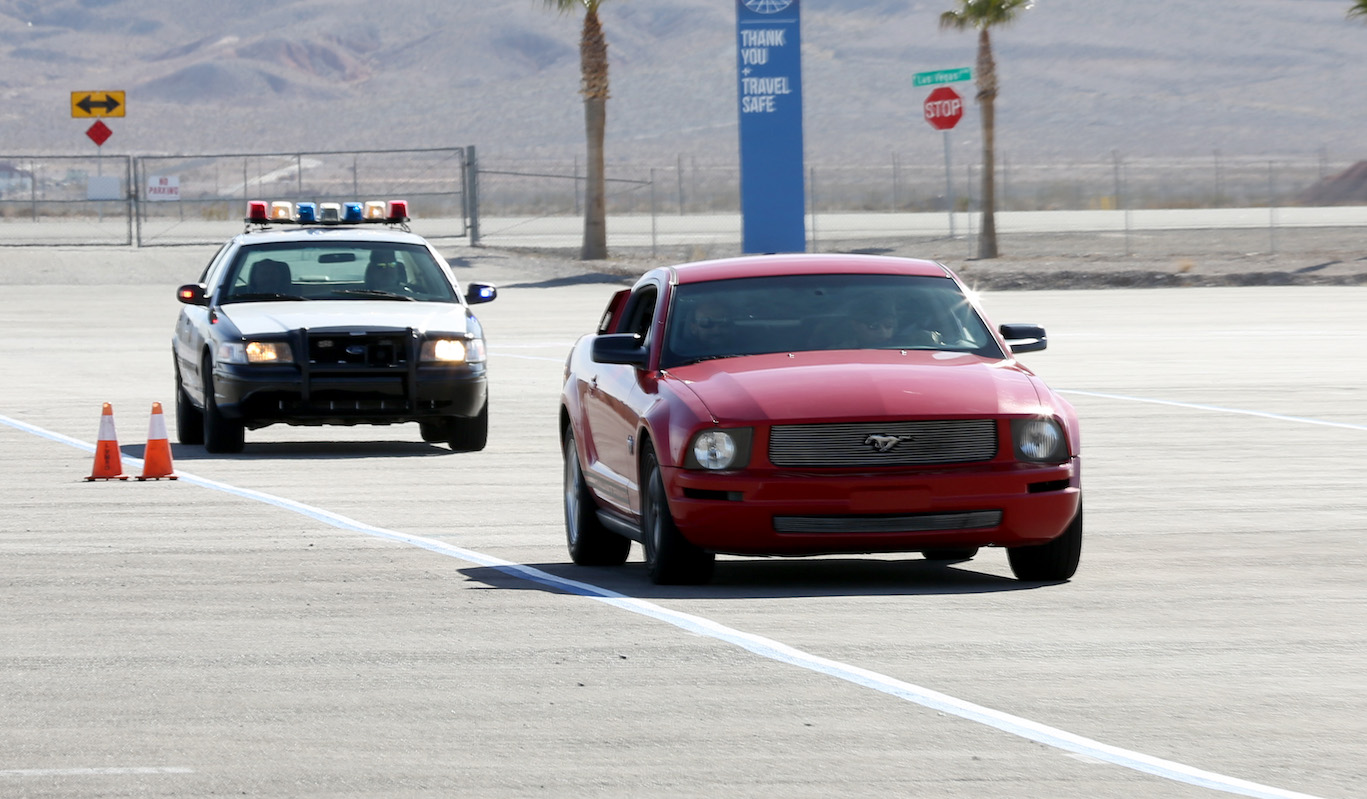 Employees demonstrate a police chase using a Police Chase Las Vegas police car pursuing a Ford Mustang at the grand opening of Police Chase Las Vegas