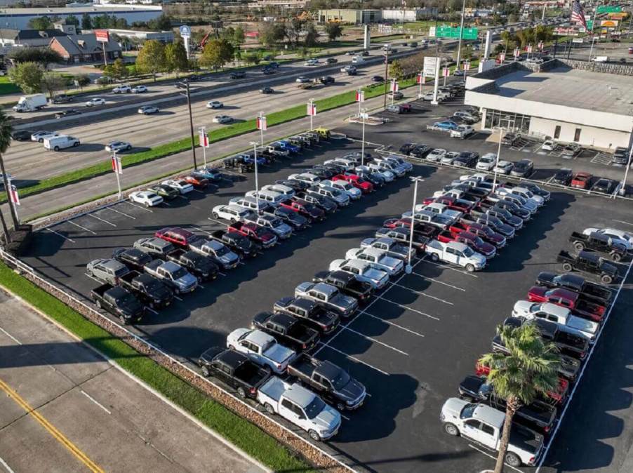 A lot of used RAM 1500 trucks, GMC Sierra 1500s, and other vehicles sit under the sun.