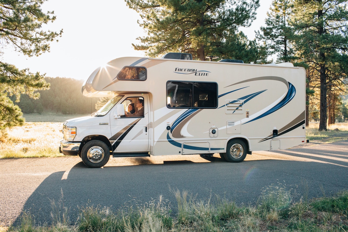 A white, brown, and blue RV driving on a sunny day.