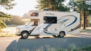 A white, brown, and blue RV driving on a sunny day.