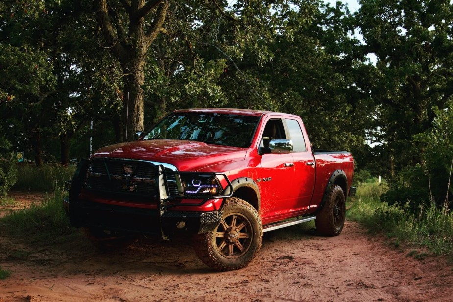 Red fourth-gen Ram 1500 pickup truck parked on the dirt of an off-road t trail.