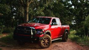 Red 4th-gen Ram 1500 pickup truck parked on a dirt trail in the woods.