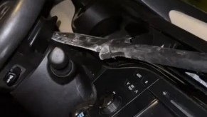 the tip of a spear through through a woman's windshield is stuck in the back of her steering wheel.