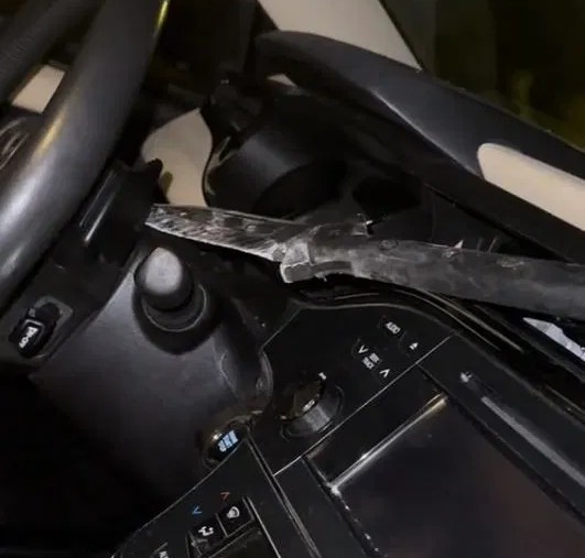 the tip of a spear through through a woman's windshield is stuck in the back of her steering wheel.