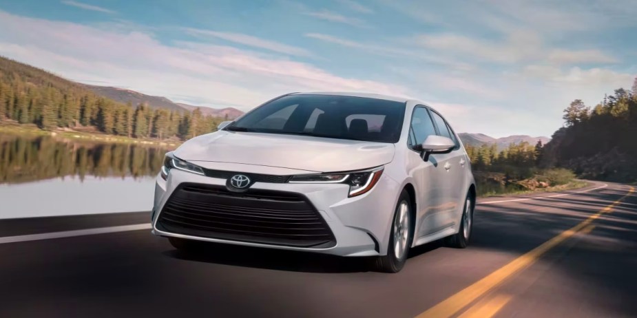 A white 2023 Toyota Corolla is driving on the road. 