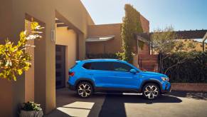 A blue Volkswagen Taos on parked outside a house.