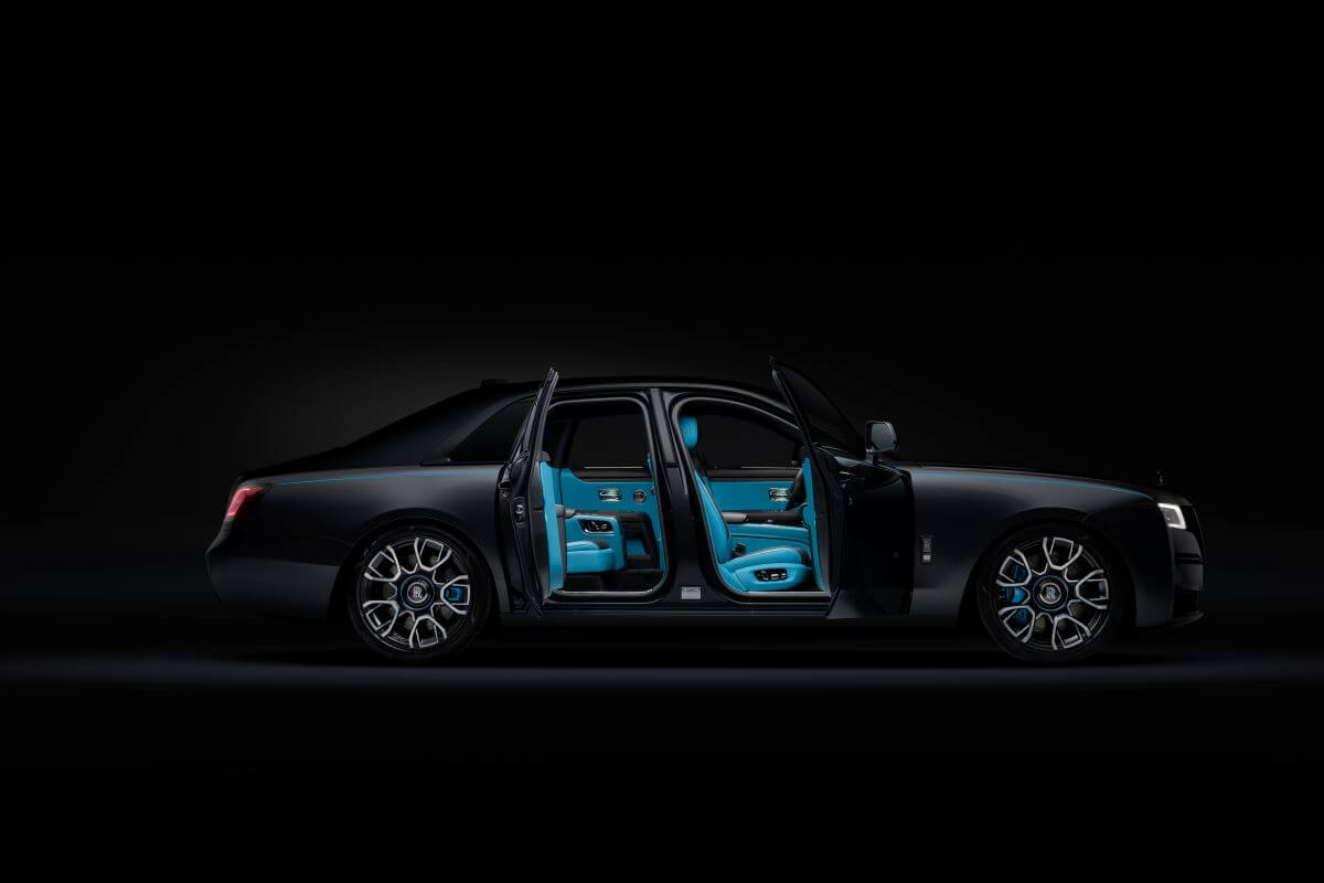 The Rolls-Royce Black Badge Ghost in a pitch black room showcasing suicide doors and blue interior