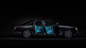 The Rolls-Royce Black Badge Ghost in a pitch black room showcasing suicide doors and blue interior