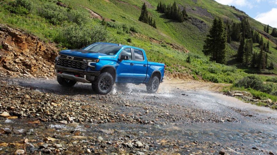 A 2024 Chevy Silverado ZR2 full-size pickup truck model driving on wet and river-run gravel and rocks