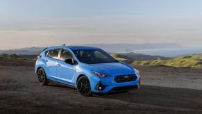 The 2024 Subaru Impreza RS hatchback model parked on a dirt cliff