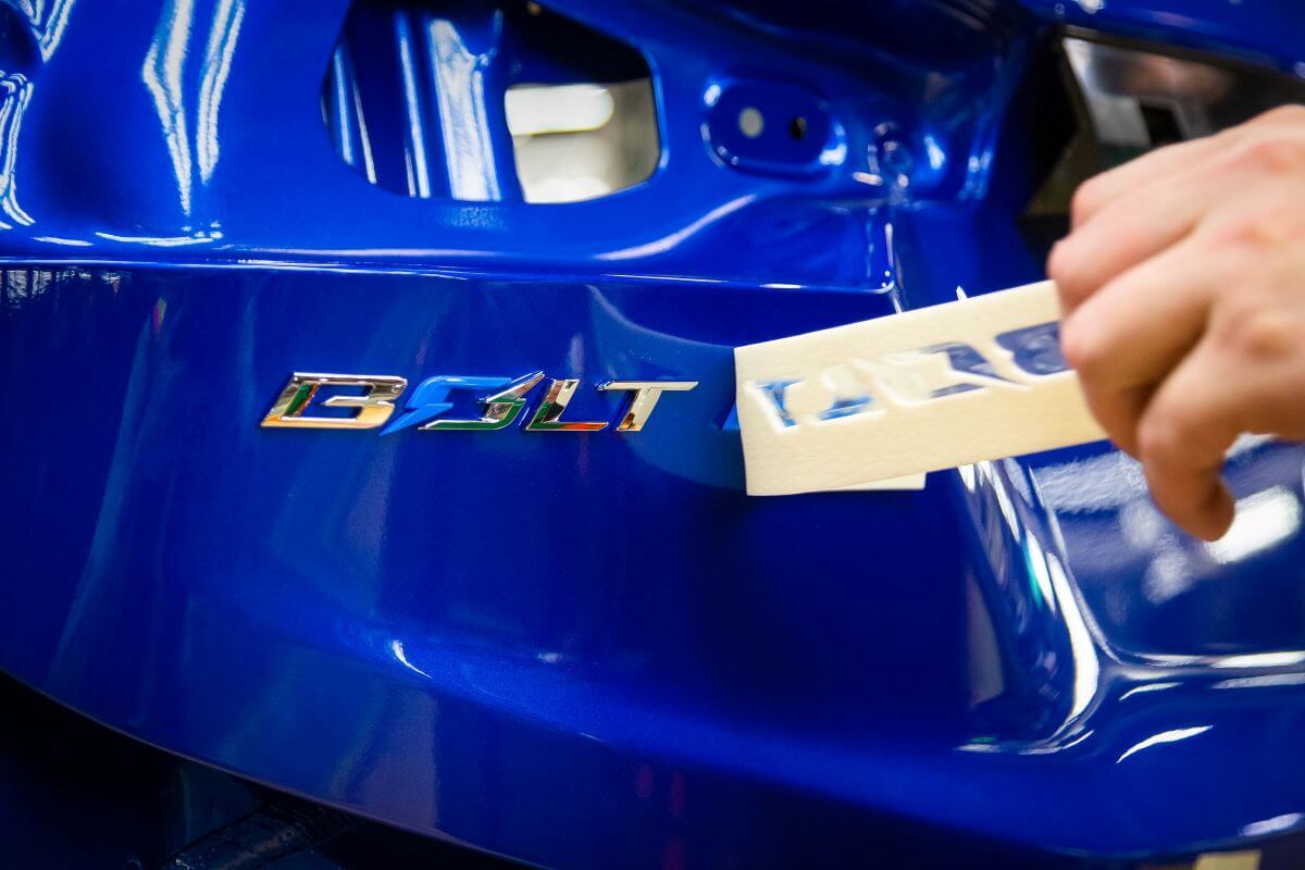 A teaser image of a blue, next-gen Chevy Bolt EV nameplate