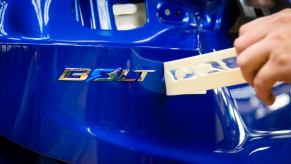 A teaser image of a blue, next-gen Chevy Bolt EV nameplate