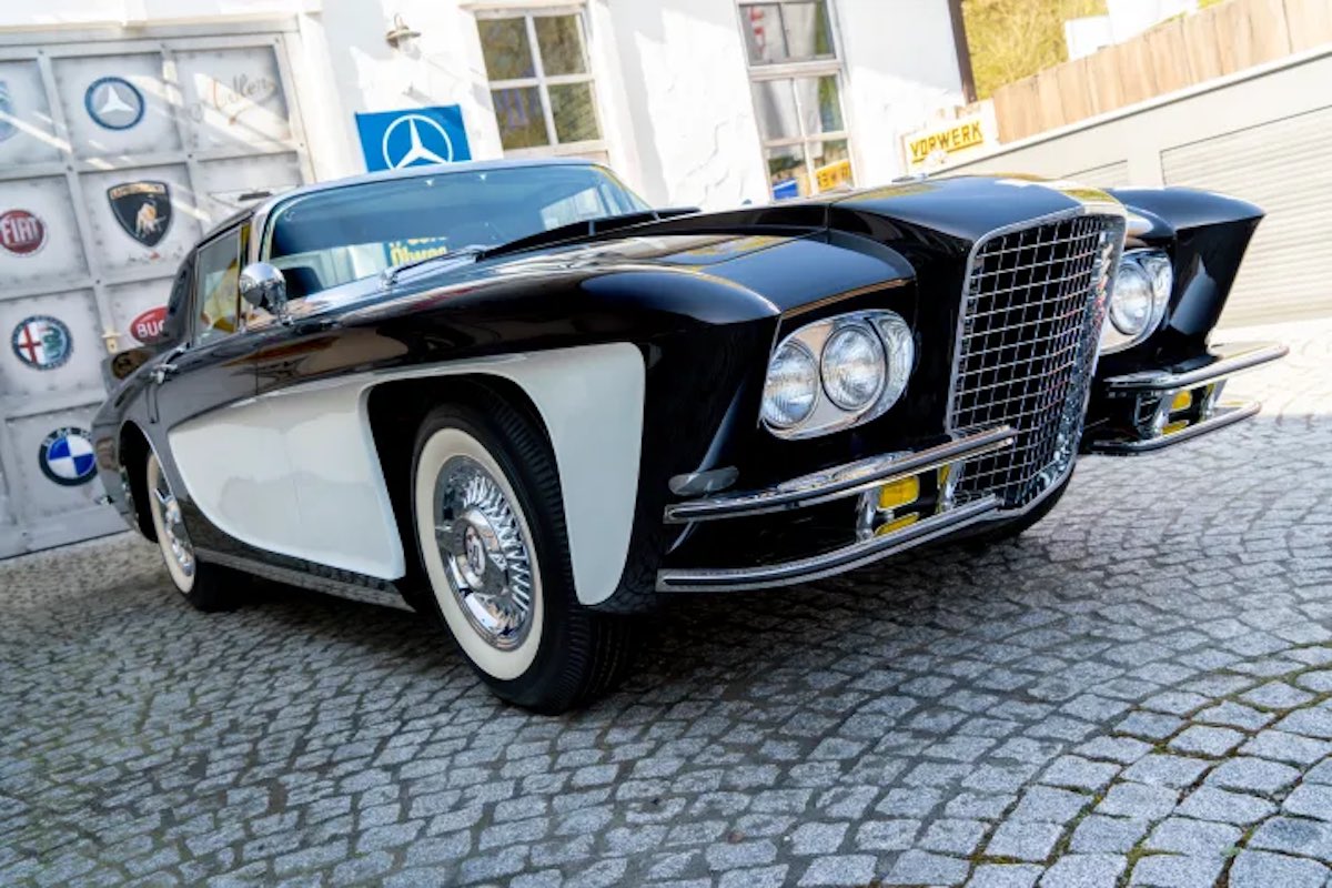 Closeup of the headlights and front fender of a Gaylord Gladiator supercar prototype parked on cobblestones.