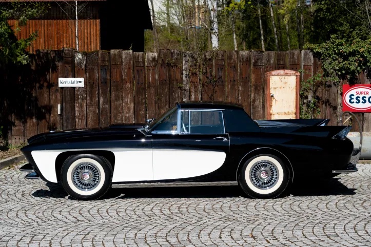 Profile view of a two-tone (black and white) Gaylord Gladiator sports car prototype parked on cobblestones.