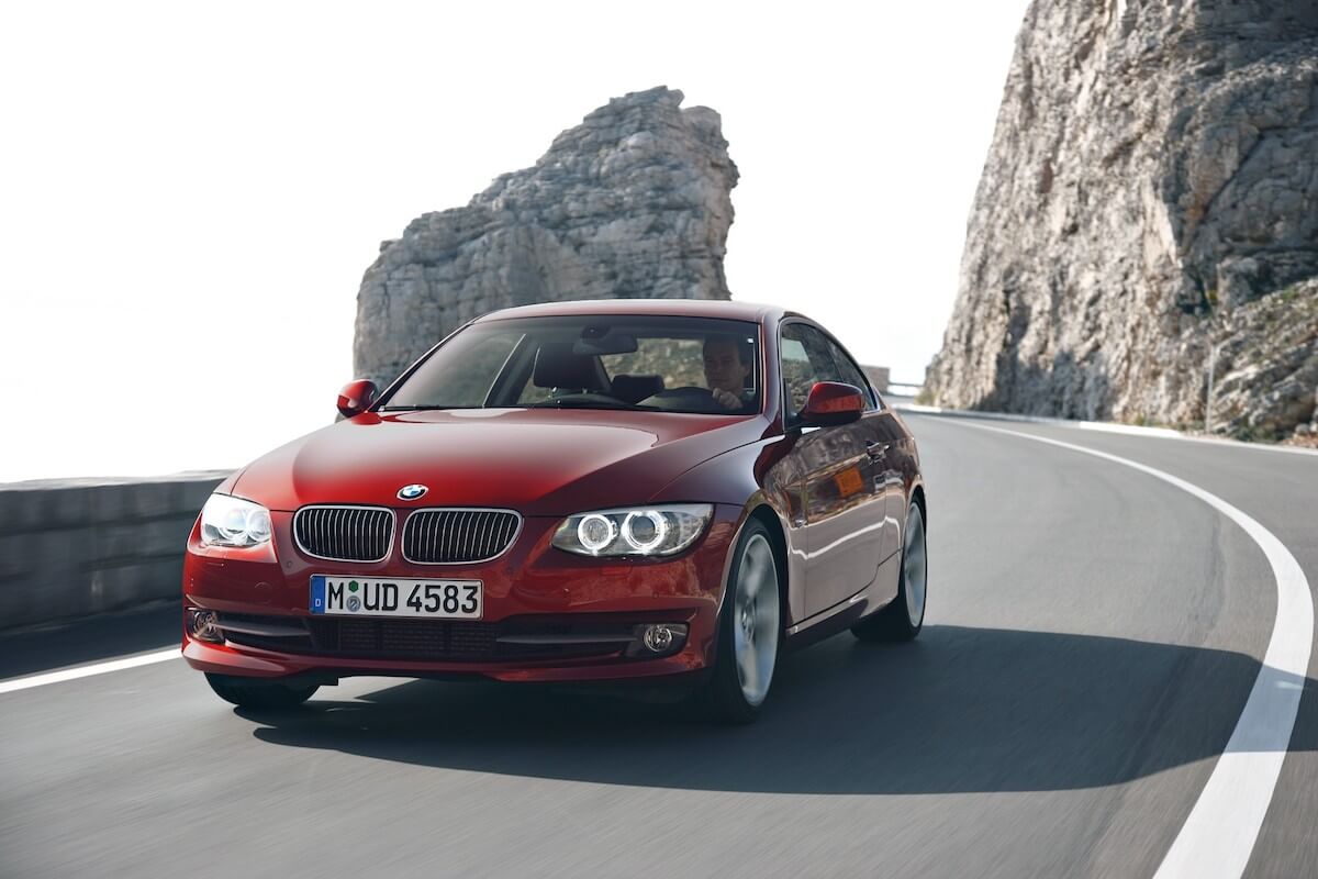 A red 2010 BMW 335i drives down the road.