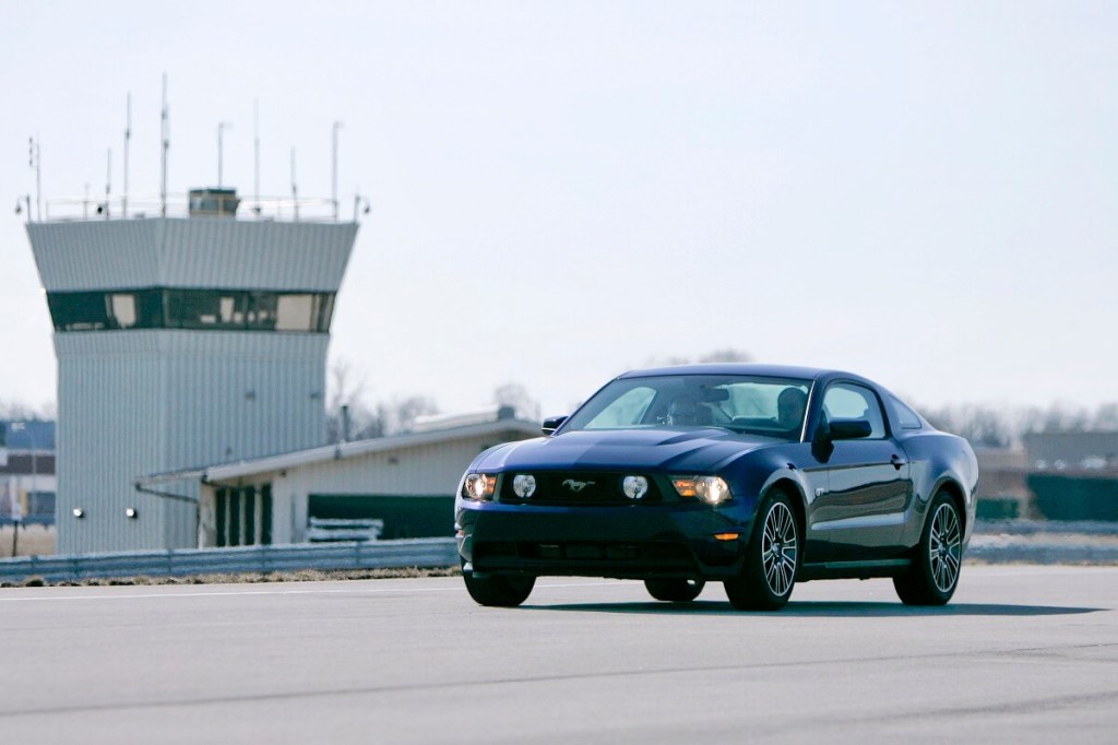 A blue 2010 Ford Mustang GT corners on a test pad.